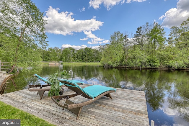 view of dock with a forest view and a water view