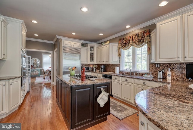 kitchen with a sink, backsplash, appliances with stainless steel finishes, and light wood finished floors