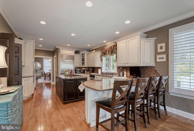 kitchen featuring tasteful backsplash, light wood finished floors, stainless steel appliances, and crown molding