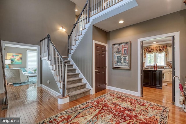 staircase featuring a high ceiling, wood finished floors, and baseboards