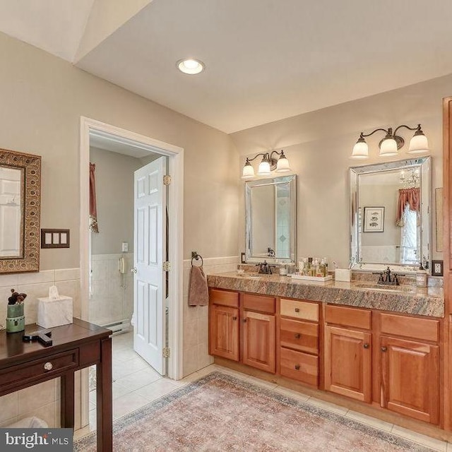 full bathroom featuring a sink, tile walls, double vanity, and tile patterned flooring