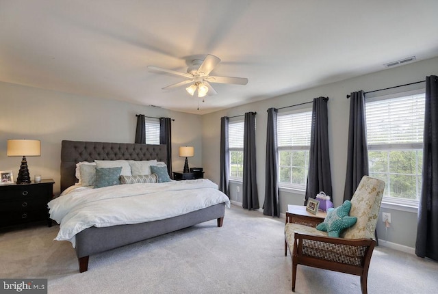 bedroom with multiple windows, light colored carpet, visible vents, and baseboards