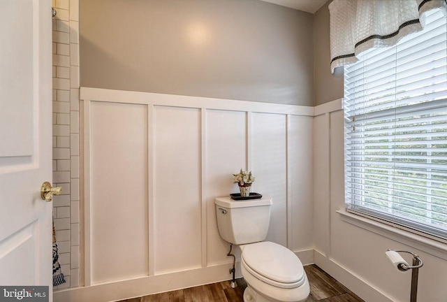 full bath featuring a decorative wall, toilet, and wood finished floors