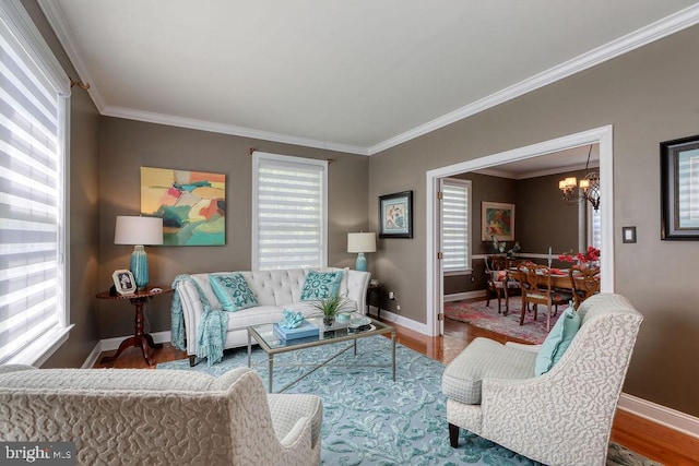 living area with baseboards, crown molding, an inviting chandelier, and wood finished floors