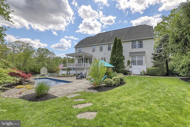 rear view of house featuring an outdoor pool, a yard, and a patio