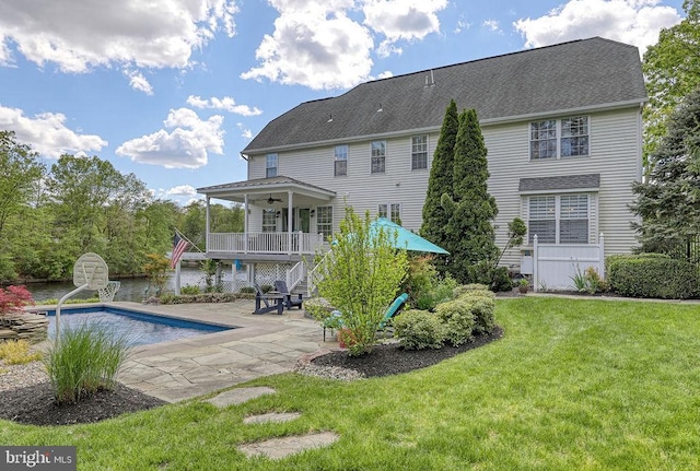 rear view of property featuring ceiling fan, stairs, a lawn, an outdoor pool, and a patio