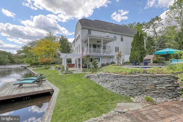 rear view of property with a patio, a yard, a ceiling fan, and a water view