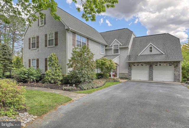 view of front facade with an attached garage, a shingled roof, stucco siding, stone siding, and aphalt driveway