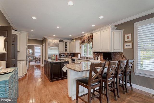 kitchen featuring light wood-type flooring, decorative backsplash, appliances with stainless steel finishes, and ornamental molding