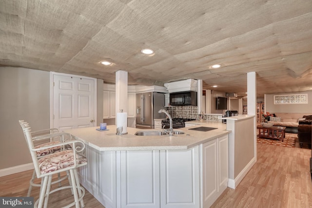 kitchen with light countertops, light wood-style floors, black microwave, and a sink