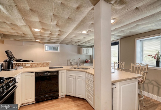 kitchen featuring black appliances, light wood-style floors, light countertops, and a sink