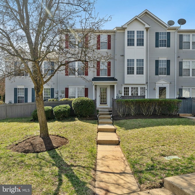 townhome / multi-family property featuring a front lawn and fence