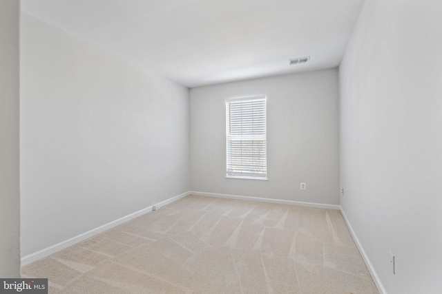 spare room featuring baseboards, visible vents, and light carpet