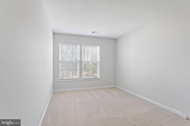 empty room with visible vents, baseboards, and light colored carpet