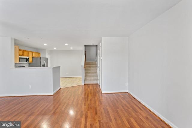 unfurnished living room with stairway, recessed lighting, baseboards, and wood finished floors