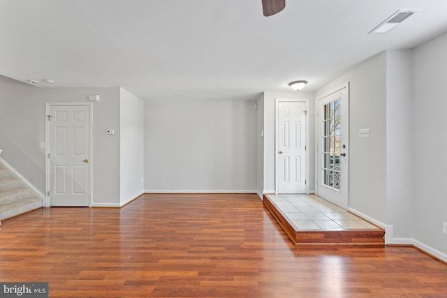 foyer featuring visible vents, ceiling fan, baseboards, stairs, and wood finished floors