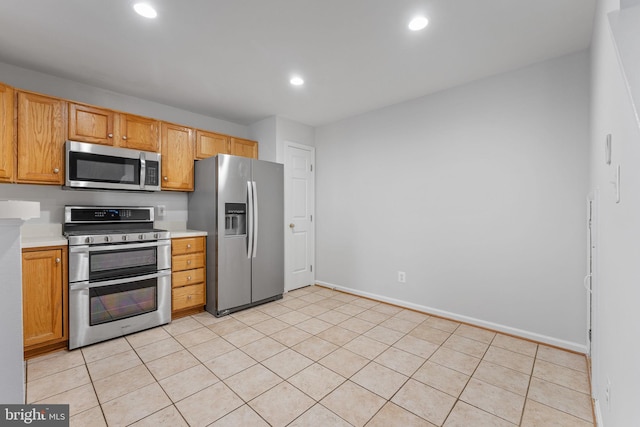 kitchen featuring baseboards, light countertops, light tile patterned floors, recessed lighting, and stainless steel appliances