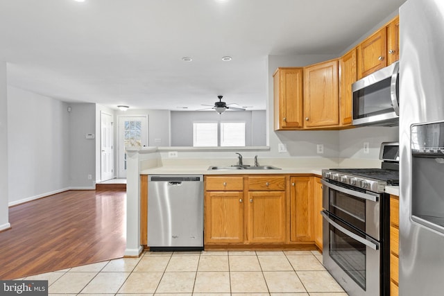 kitchen with ceiling fan, light tile patterned floors, a peninsula, stainless steel appliances, and a sink