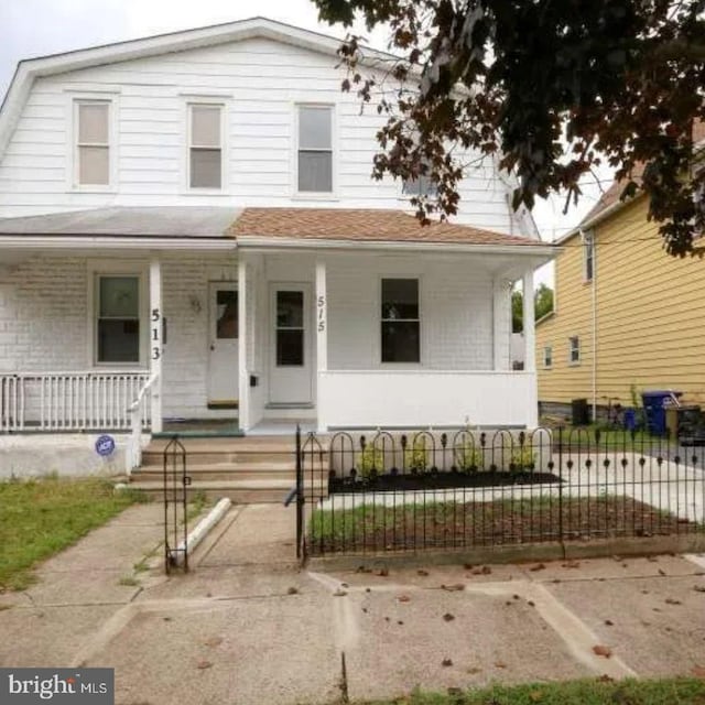 view of front of home featuring covered porch, a fenced front yard, and a gambrel roof