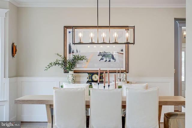 dining area with ornamental molding and wainscoting