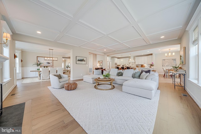 living area featuring visible vents, light wood-style flooring, coffered ceiling, recessed lighting, and a chandelier