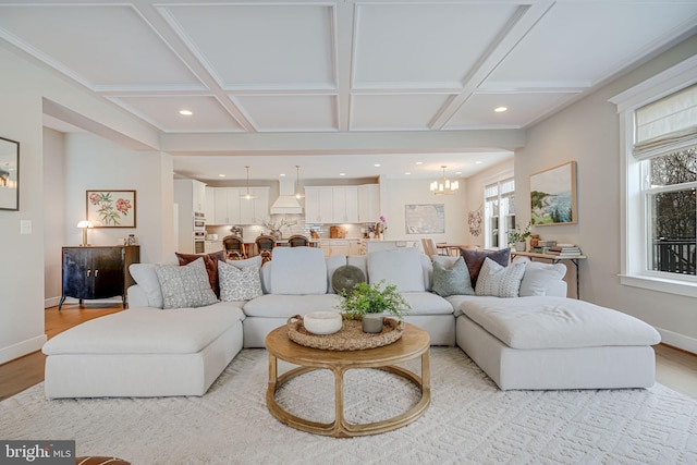 living area with a wealth of natural light, light wood finished floors, baseboards, and coffered ceiling