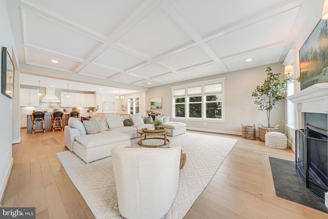 living room featuring recessed lighting, a fireplace with flush hearth, coffered ceiling, and light wood finished floors