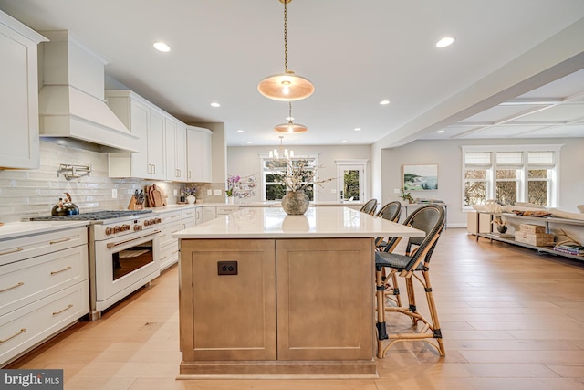 kitchen featuring a kitchen island, high end white range oven, a breakfast bar area, light countertops, and custom exhaust hood