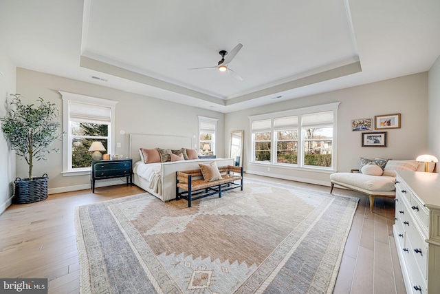 bedroom featuring light wood-type flooring and a raised ceiling