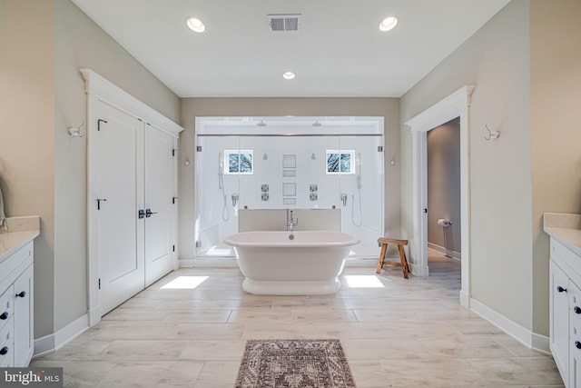 full bathroom featuring visible vents, recessed lighting, baseboards, a soaking tub, and vanity