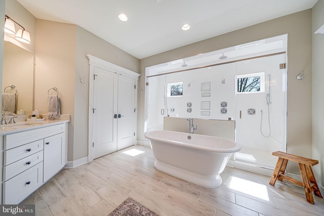 bathroom with a stall shower, recessed lighting, vanity, a freestanding bath, and wood tiled floor