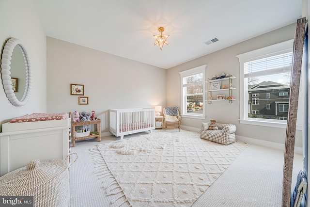 carpeted bedroom with visible vents, a crib, and baseboards