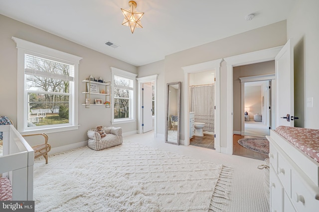 bedroom with visible vents, ensuite bathroom, and baseboards