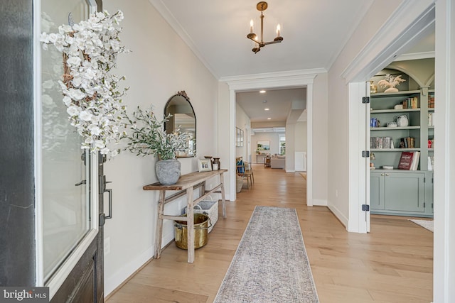 entryway with a notable chandelier, light wood-style floors, baseboards, and ornamental molding