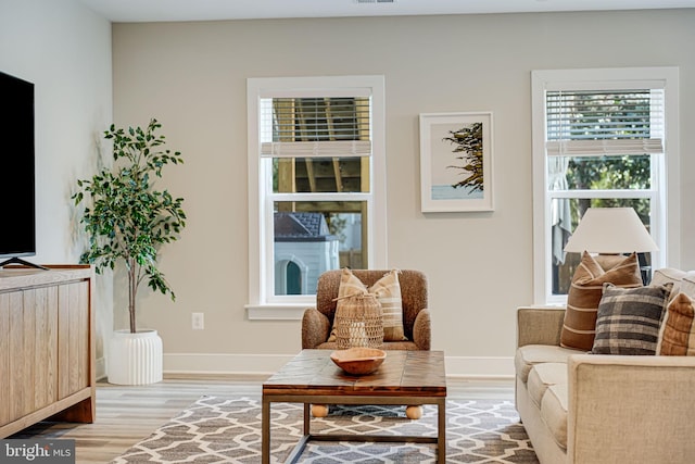 living area with light wood-style flooring, visible vents, and baseboards