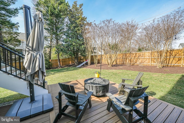 wooden deck with a fire pit, a fenced backyard, and a lawn