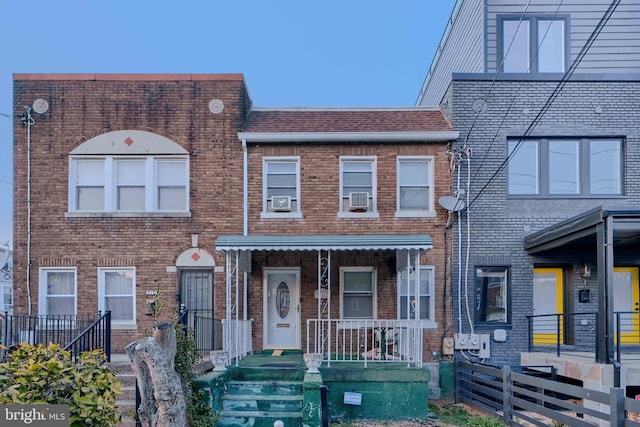 multi unit property with a porch, fence, and brick siding