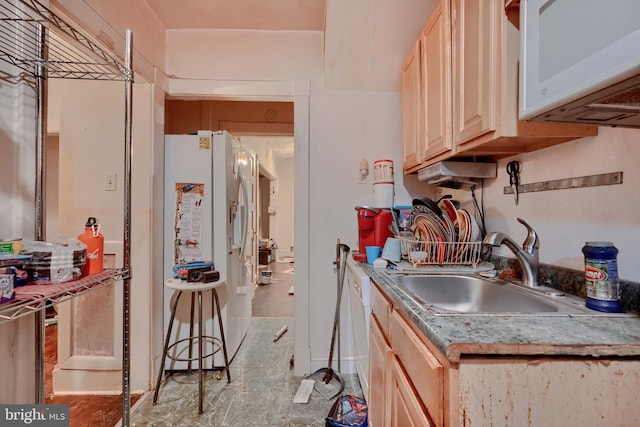 kitchen with light brown cabinets, white appliances, and a sink