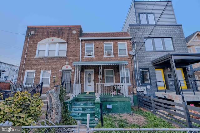 multi unit property with brick siding and a fenced front yard