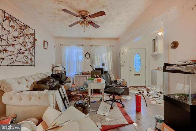 living area with a textured ceiling, ceiling fan, and wood finished floors