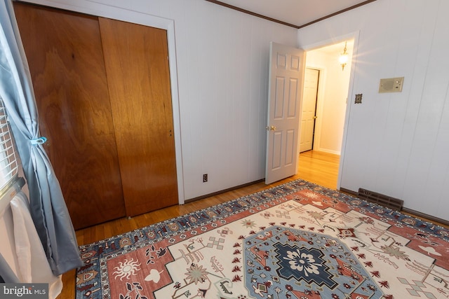 bedroom featuring visible vents, baseboards, ornamental molding, wood finished floors, and a closet