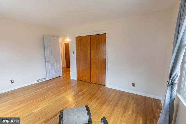 bedroom featuring a closet, baseboards, visible vents, and light wood finished floors