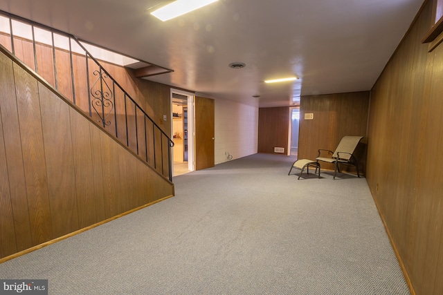 unfurnished room featuring stairway, visible vents, wood walls, and carpet floors