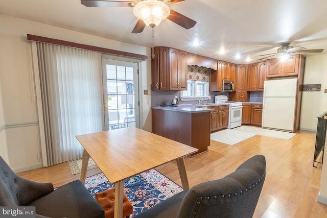 kitchen with a sink, white appliances, light wood-style floors, and ceiling fan