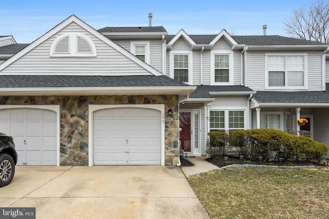 view of property with stone siding, concrete driveway, a garage, and a shingled roof