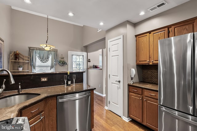 kitchen with visible vents, decorative backsplash, brown cabinets, appliances with stainless steel finishes, and a sink