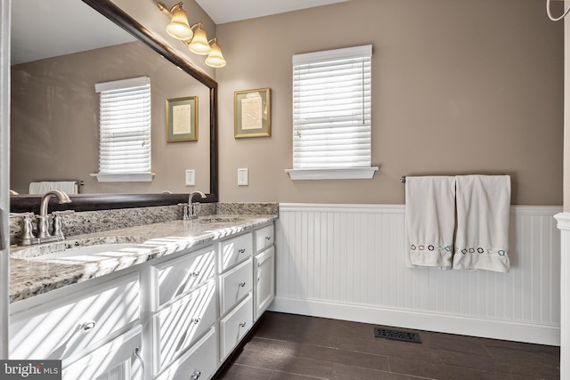 full bathroom featuring a wainscoted wall, wood finished floors, visible vents, and a sink