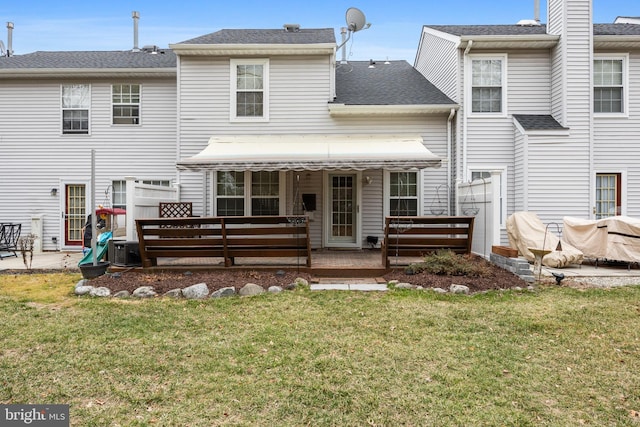 back of property featuring a yard and roof with shingles