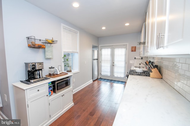 kitchen featuring backsplash, dark wood finished floors, light countertops, stainless steel appliances, and white cabinetry