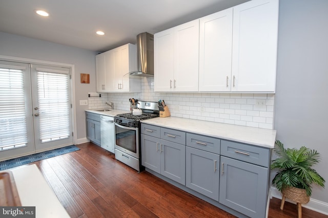 kitchen with backsplash, dark wood-style floors, stainless steel appliances, wall chimney exhaust hood, and a sink